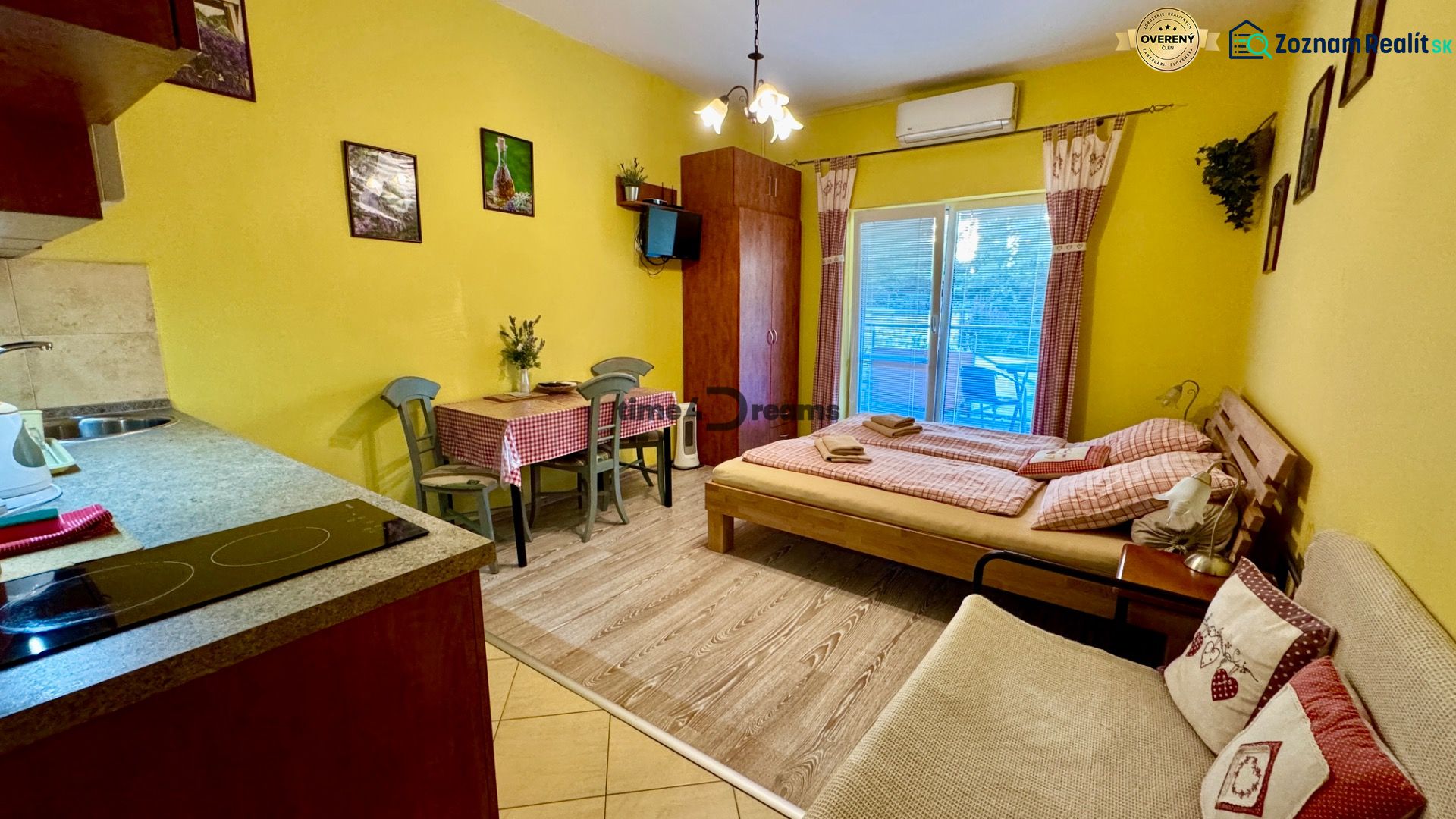 Interior of a holiday apartment with a wood-decorated floor, dining table, and bed.