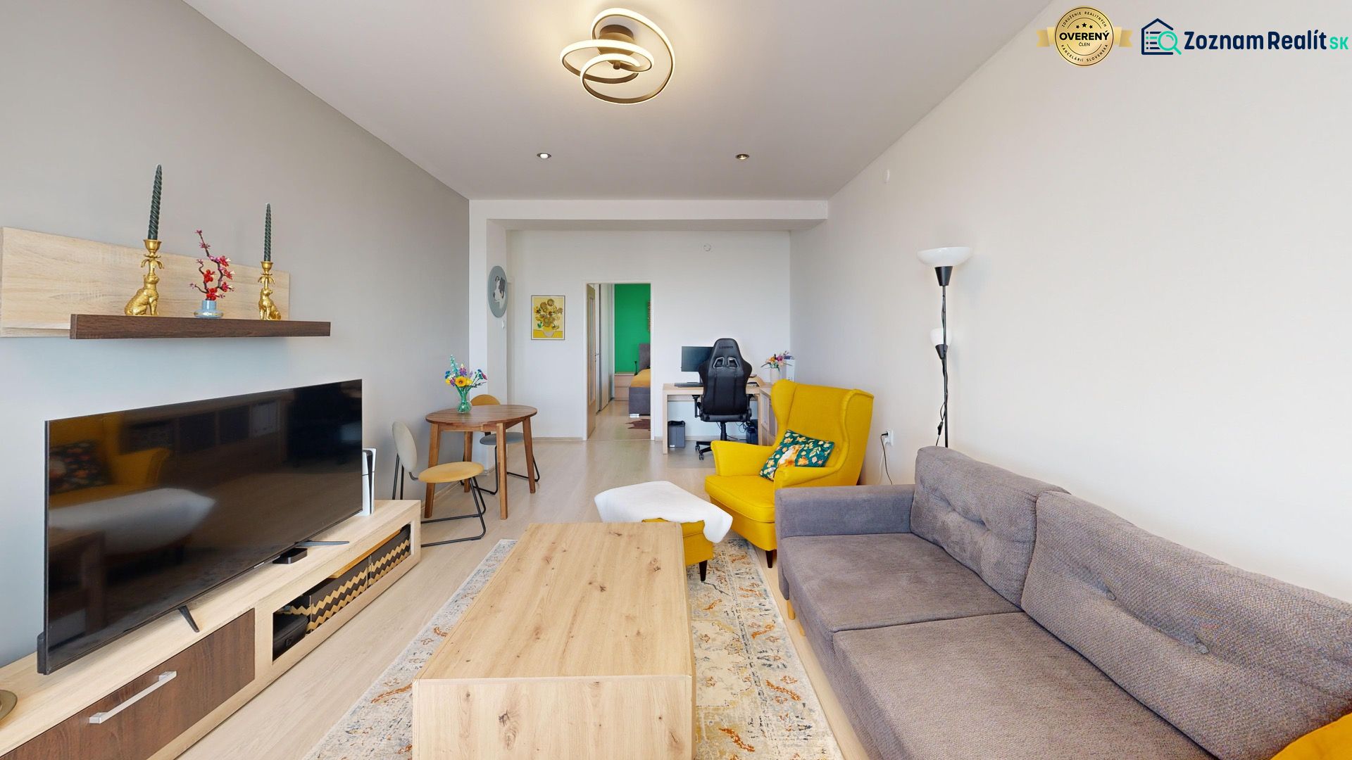 Living room in a two-room apartment with a wooden decor floor and a colorful armchair.