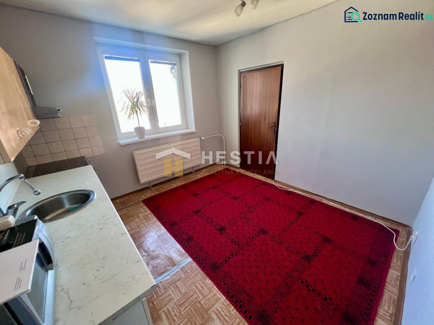 A kitchen in a 3-room apartment with carpet and wooden decor flooring.