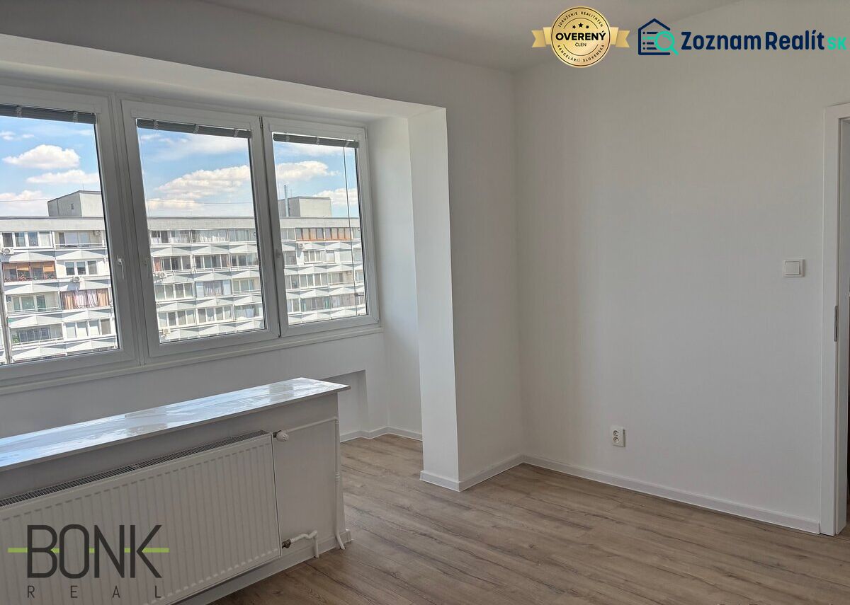 A bright room with large windows and a wooden decor floor in a 2-room apartment.