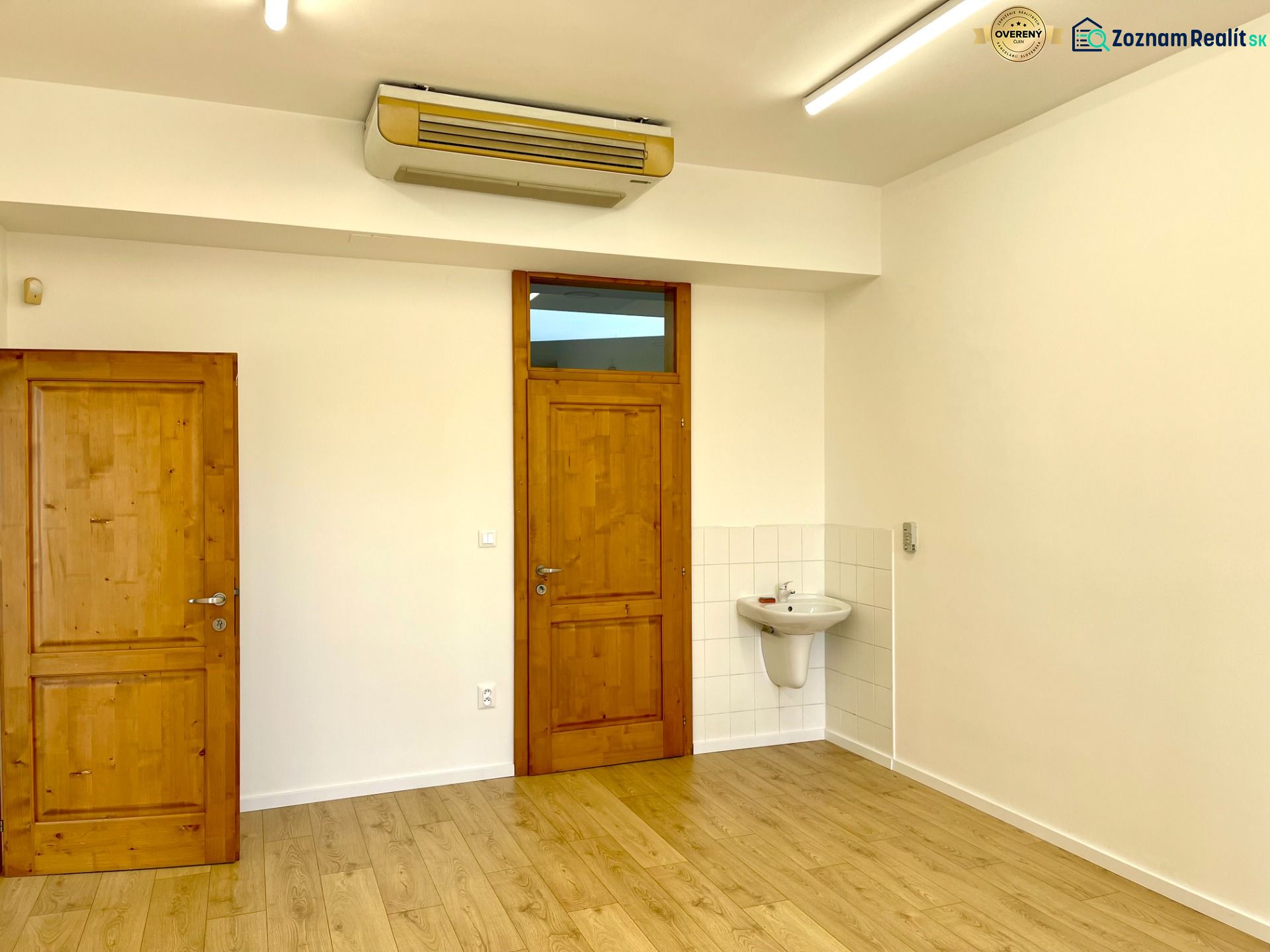 Offices with wooden doors, light walls, and a floor with a wooden design.