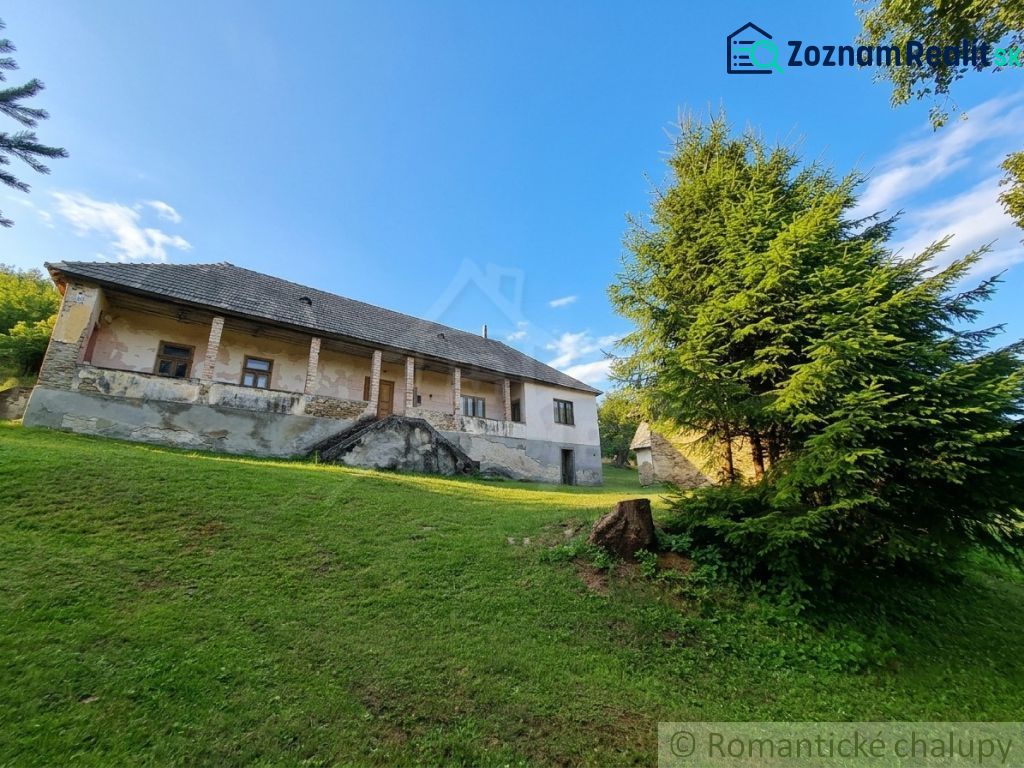 A family house in Dobroč with an extensive lawn and trees on a sloping plot.