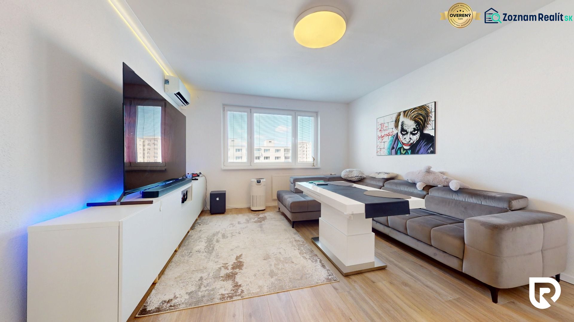 Living room in a 3-room apartment with a large sofa, television, and wooden decor flooring.
