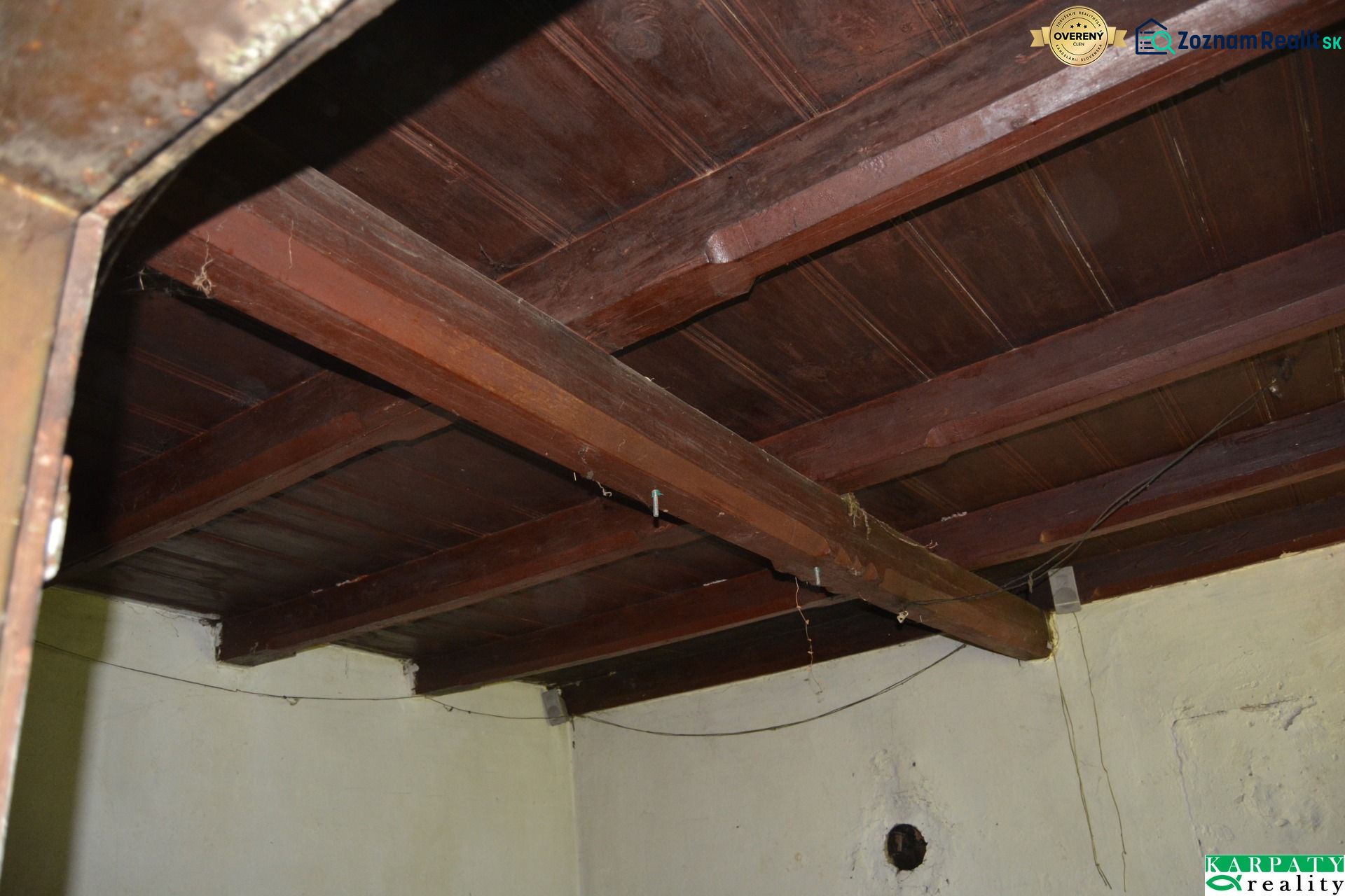 Wooden ceiling in the interior of a family house with rough plaster and electrical cables.