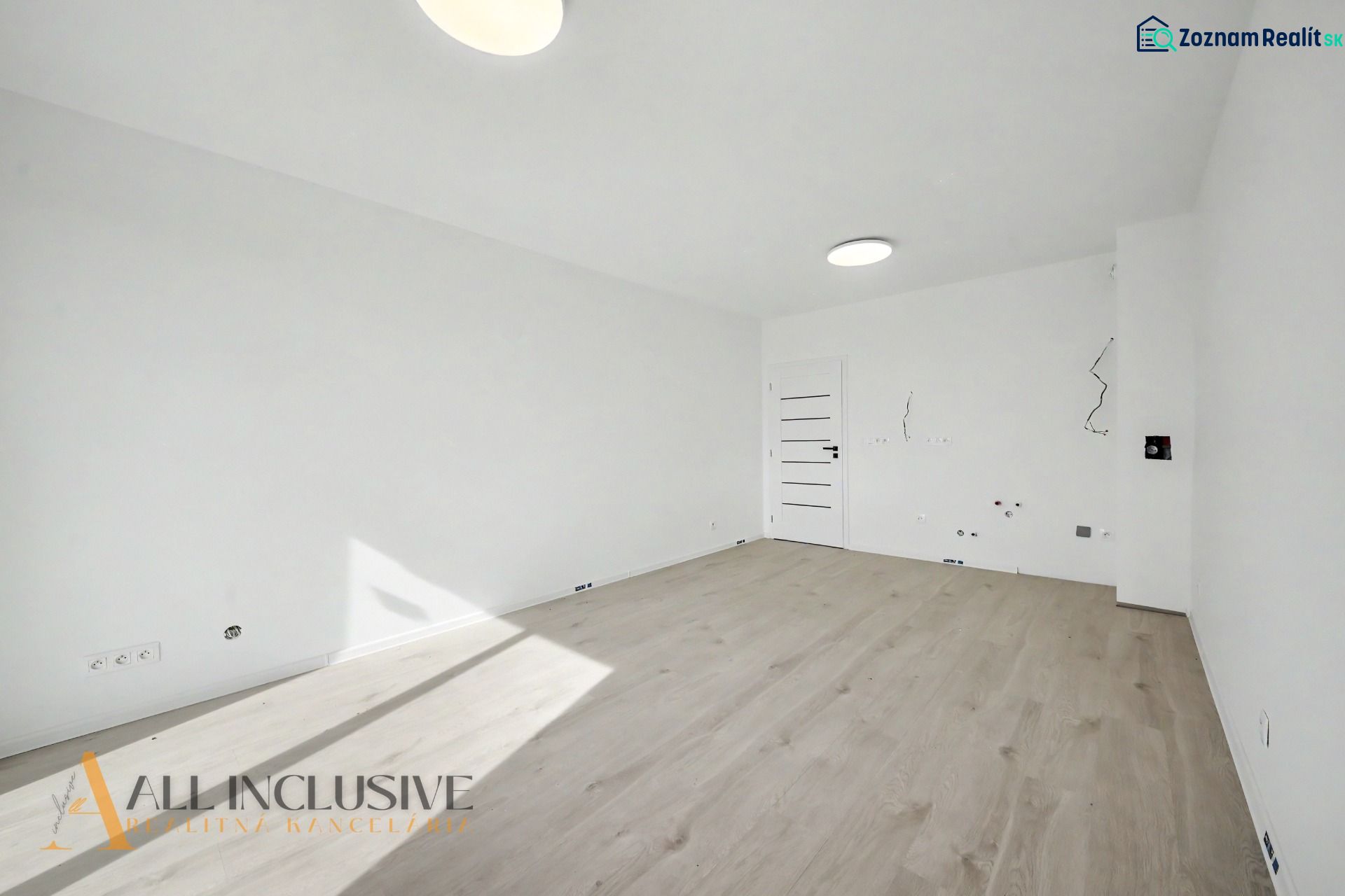 A room with white walls and a wooden decor floor in a 2-room apartment.