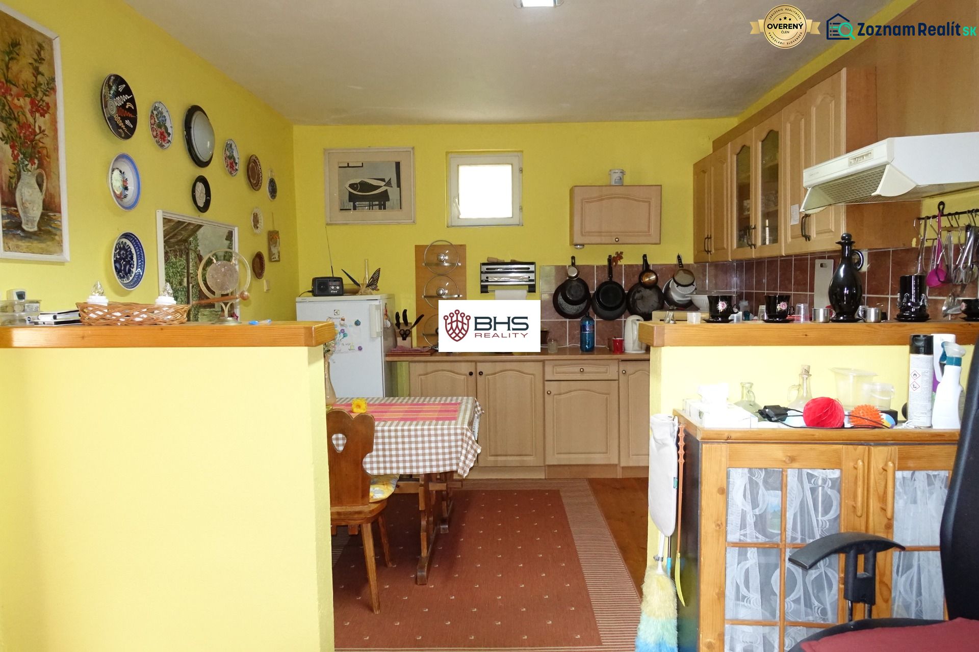 A kitchen in a family house with wooden decor, yellow walls, and decorative plates.