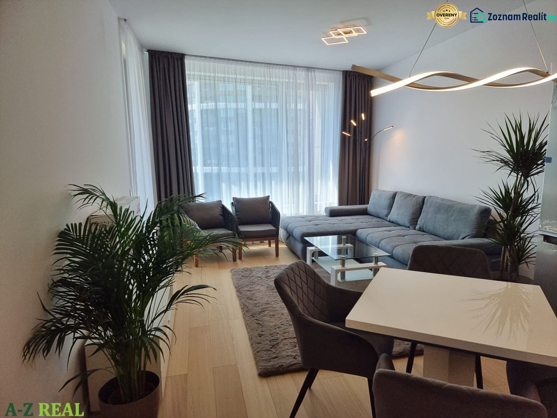 Living room in a 2-room apartment with a corner sofa, dining table, and wooden decor flooring.