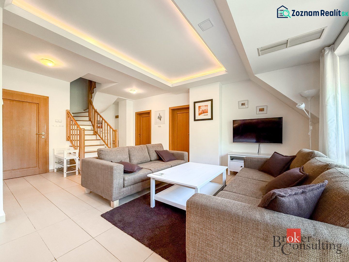 Living room with wood-patterned flooring, staircase, and sofa in a 5 or more room apartment.