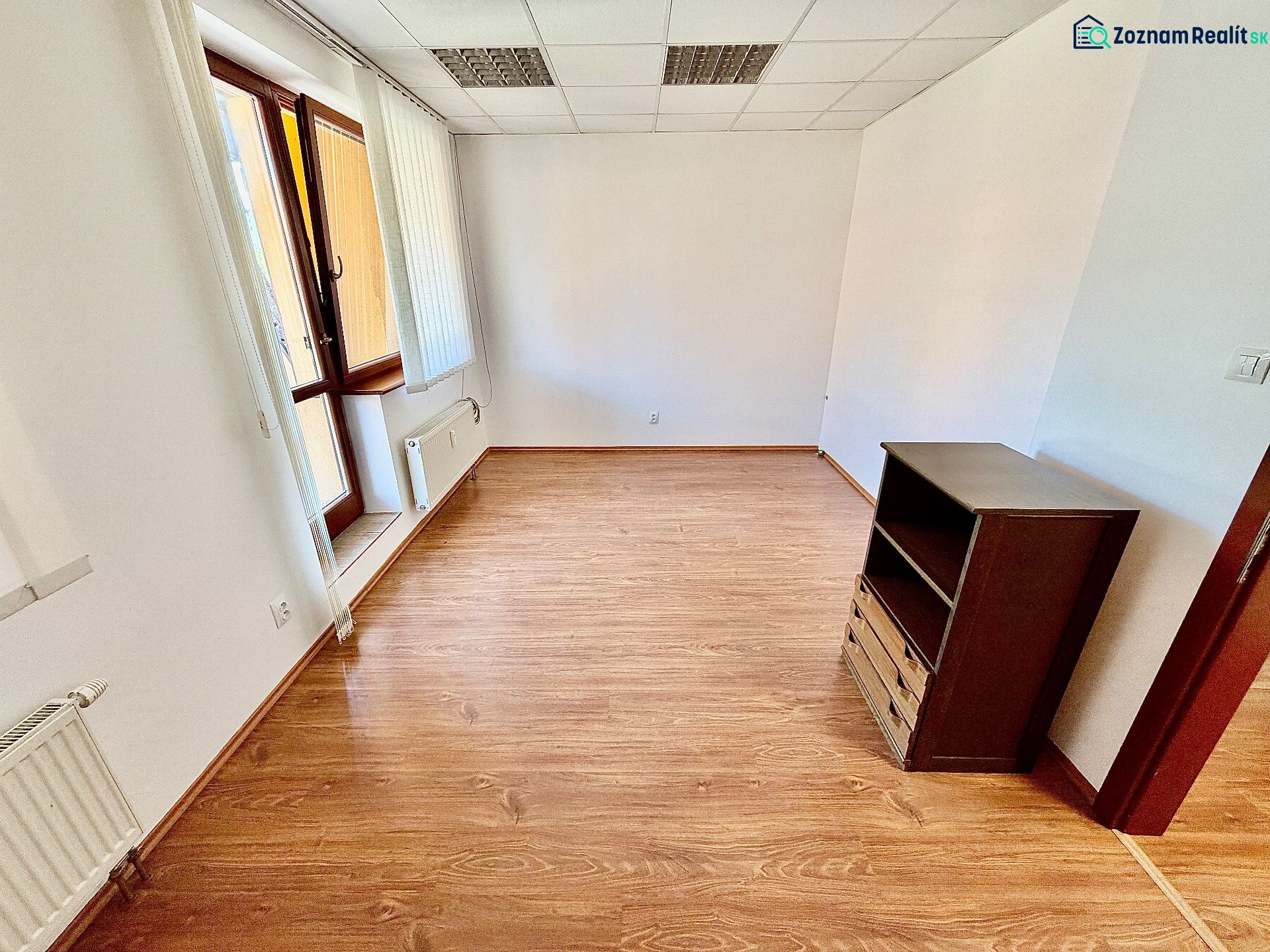 Offices with wood-patterned flooring, illuminated by a large window, and storage space.