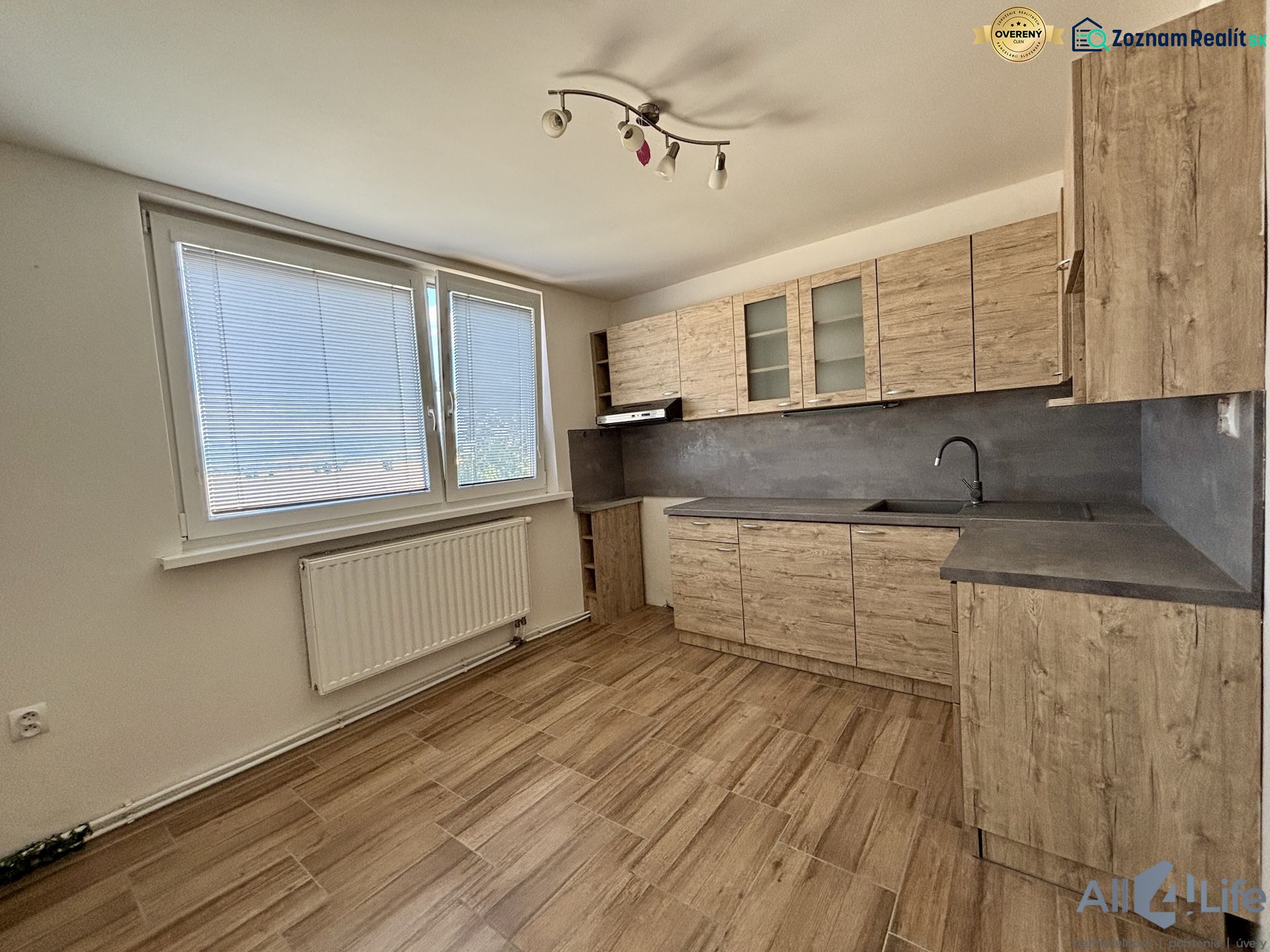 A kitchen in a 3-room apartment with a wooden decor floor and large windows.