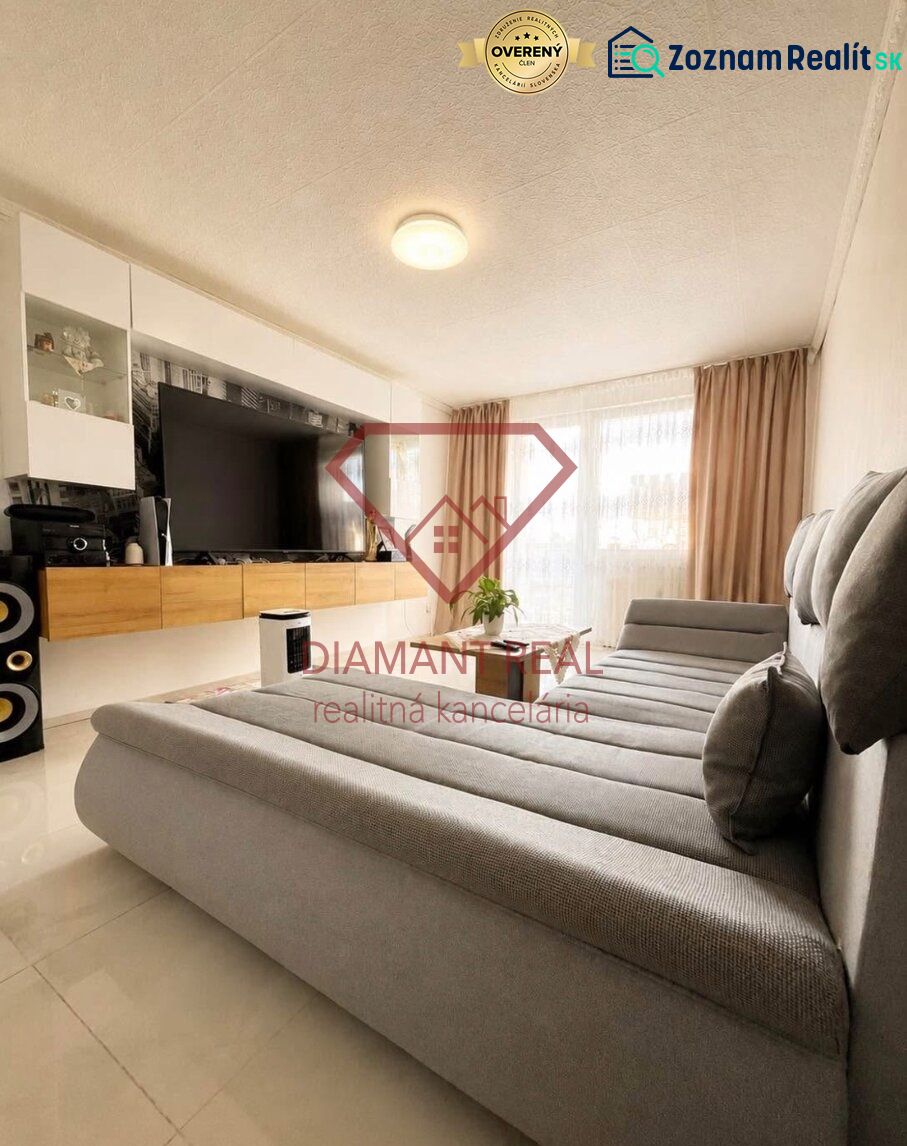 Living room in a two-room apartment with a large sofa and a TV on the wall.