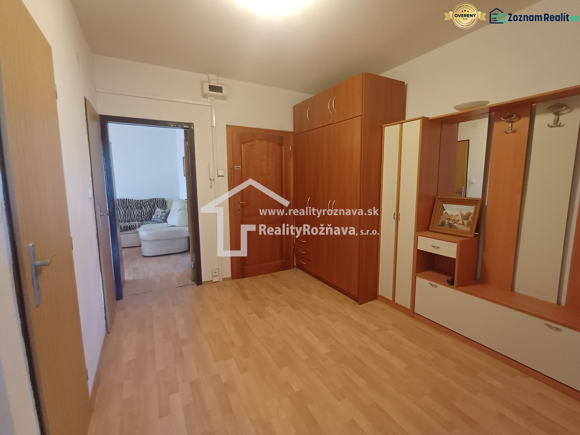 A hallway with a wooden decor floor and furniture in a 3-room apartment.