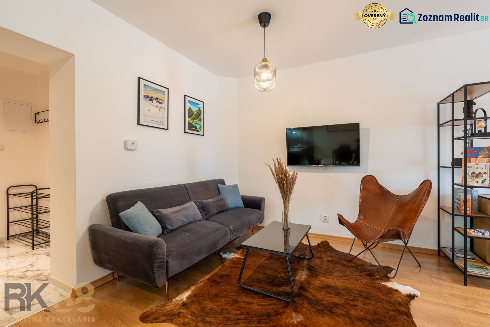 Living room in a two-room apartment with a wooden decor floor and a leather armchair.