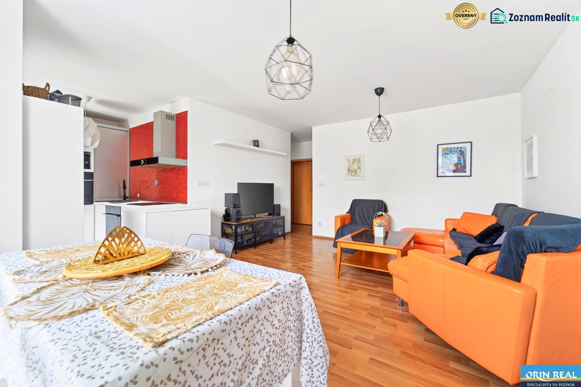 Living room with a sofa and a kitchenette in a 3-room apartment with a wooden decor floor.