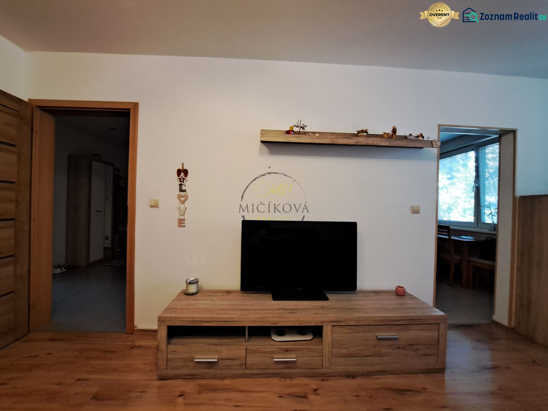 Living room in a 3-room apartment with a wood-patterned floor and a television on a cabinet.