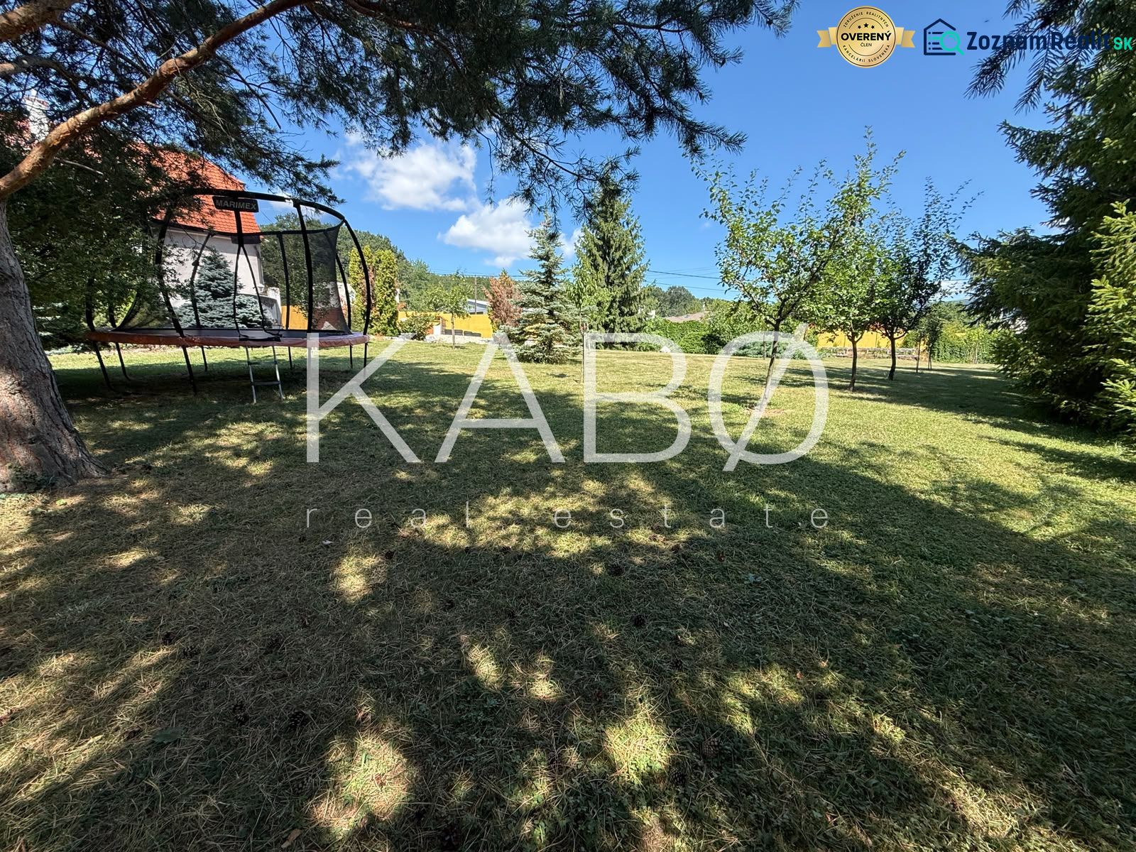 The garden of a family house in Čaradice with a trampoline and fruit trees.