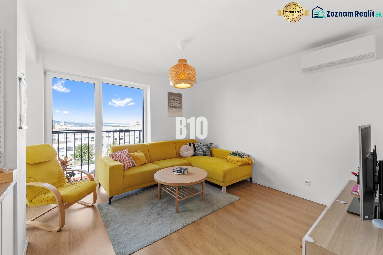Living room of a 4-room apartment with a yellow sofa and a large window, floor with wooden decor.