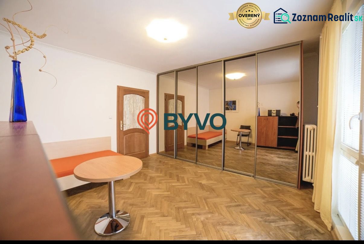 A room in a 3-room apartment with a wooden decor floor and a large mirrored wardrobe.