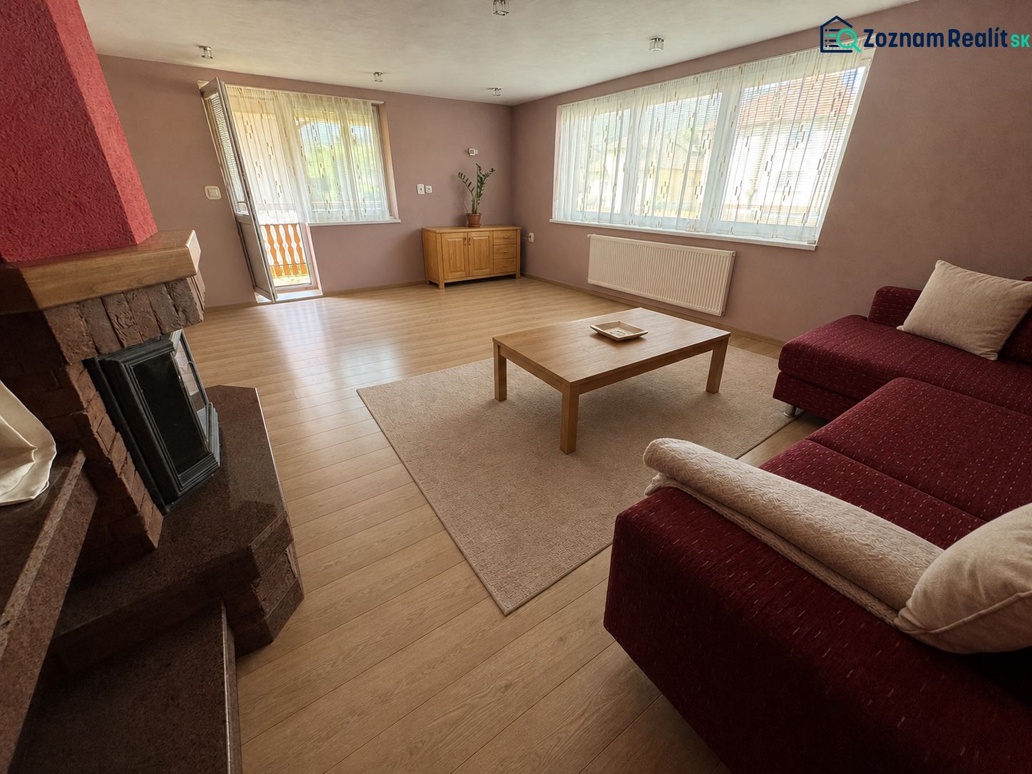 Living room in a family house with a sofa, fireplace, and wooden decor flooring.