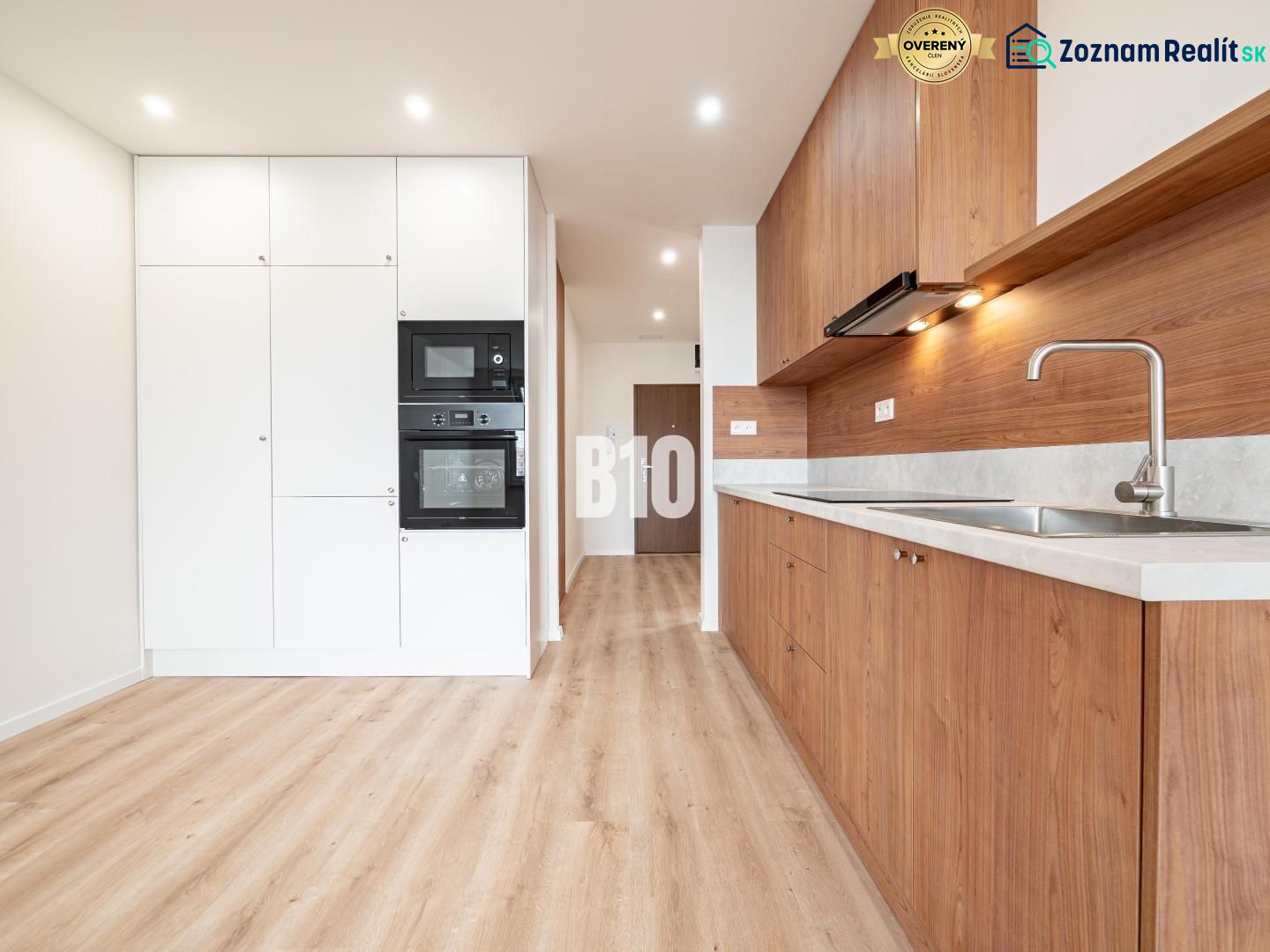 A kitchen in a 3-room apartment with white cabinets and a wood-patterned floor.