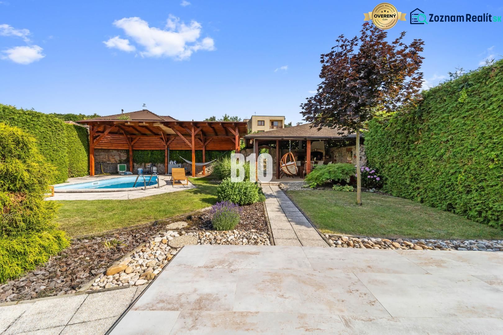 A garden of a family house in Nitra with a swimming pool and a gazebo surrounded by greenery.