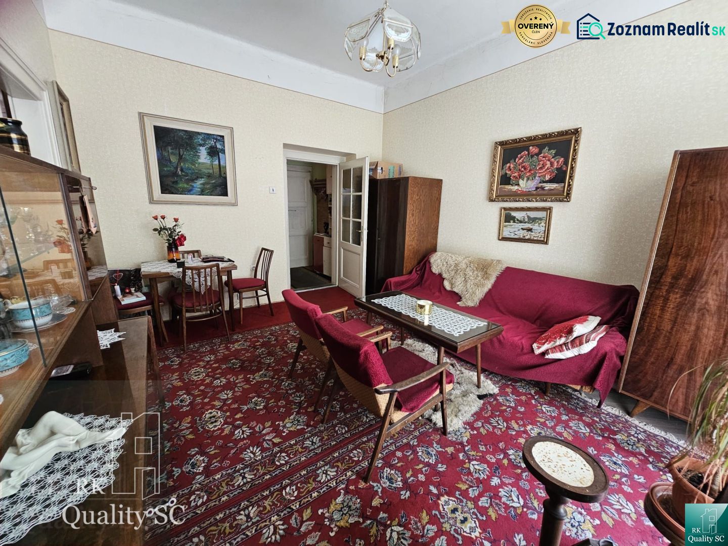 Living room in a 2-room apartment with a carpet and wooden furniture, paintings on the walls.
