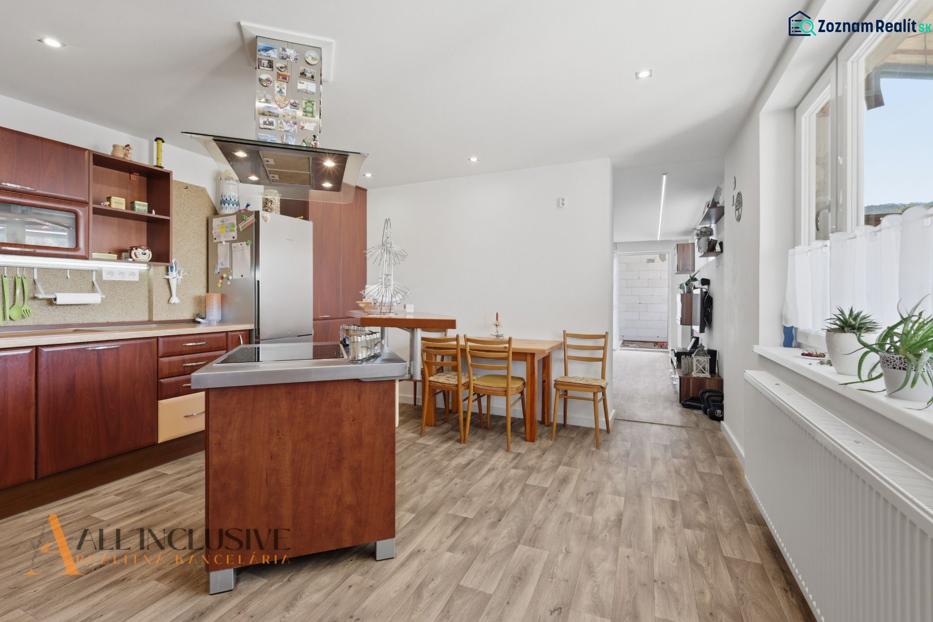 A kitchen in a family house with wooden floor decor, a dining table, and modern appliances.