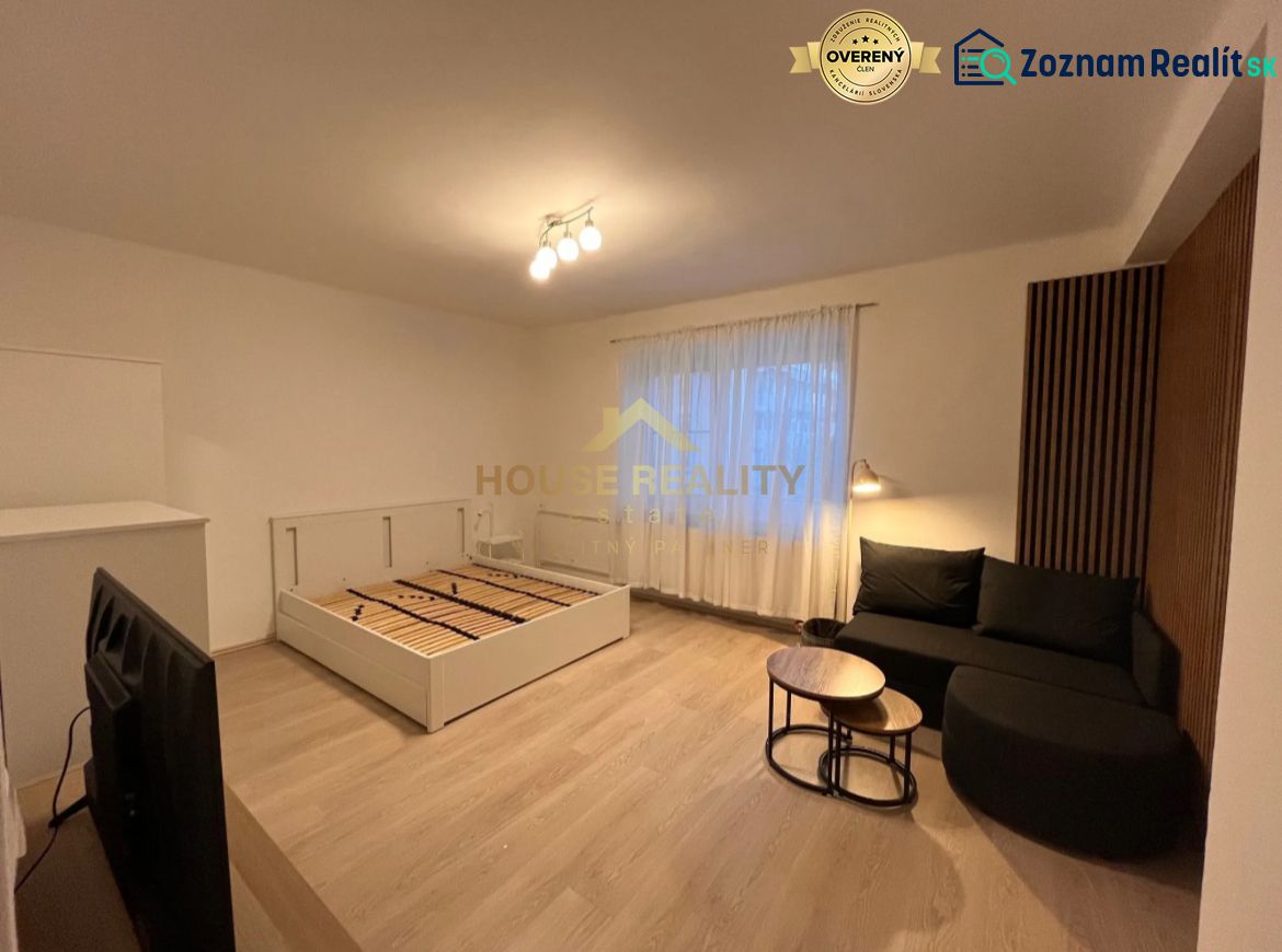 Interior of a 1-room apartment with a wooden decor floor, sofa, and bed.