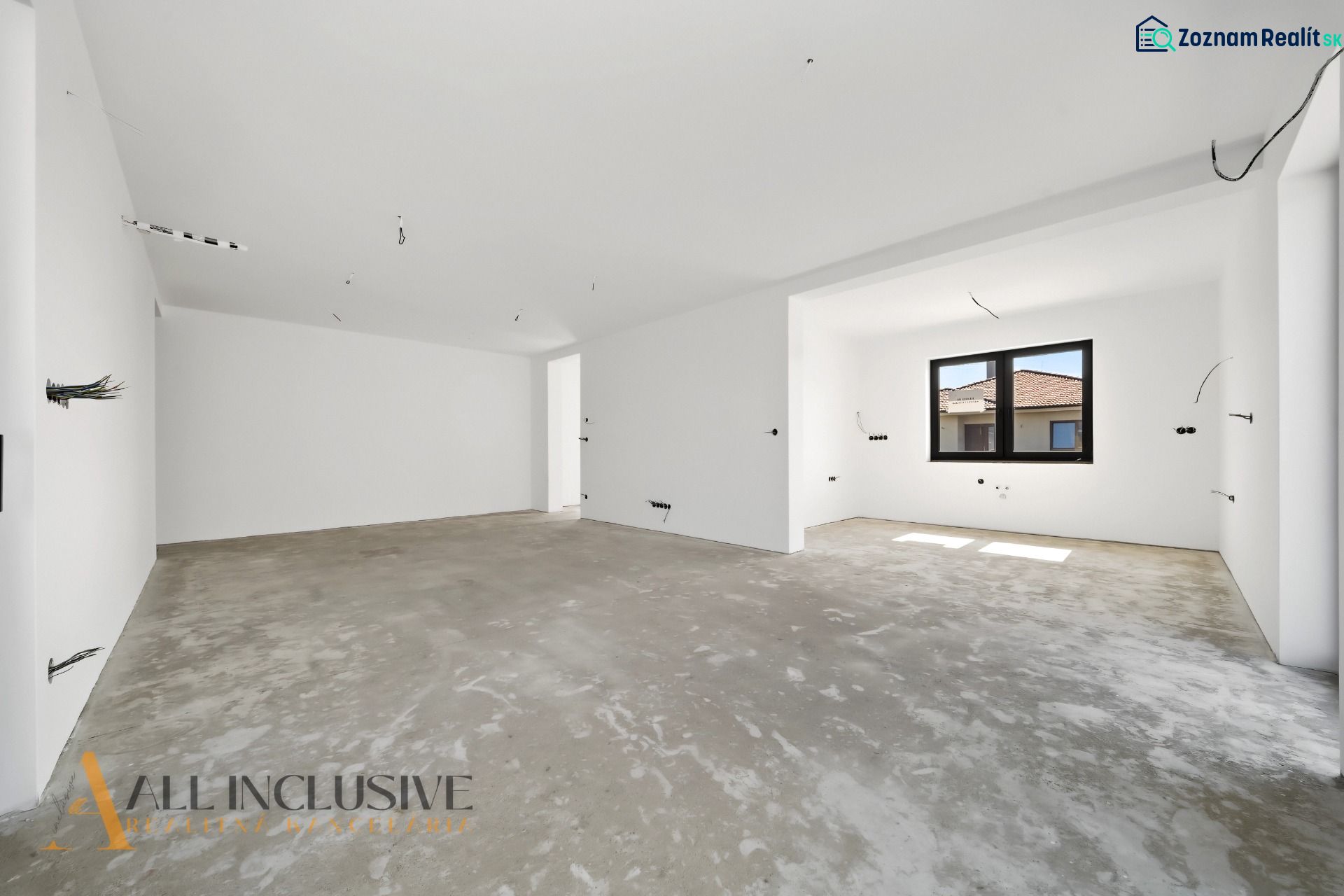 A spacious room in a family house with a concrete floor and a large window.