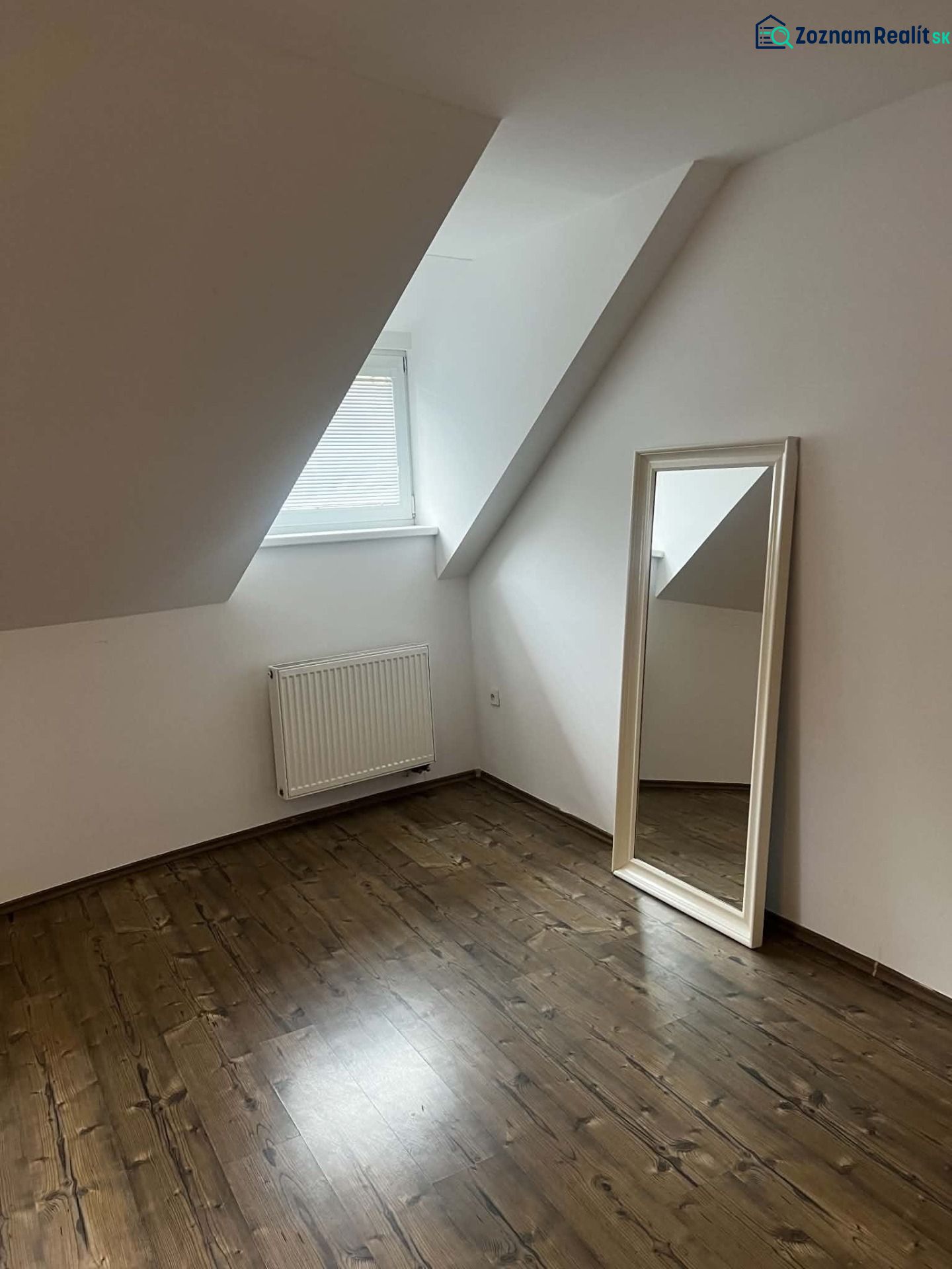 Attic room with wooden decor flooring and a large mirror in a 2-room apartment.
