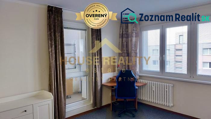 Room in a studio apartment with large windows, an office chair, and a desk.