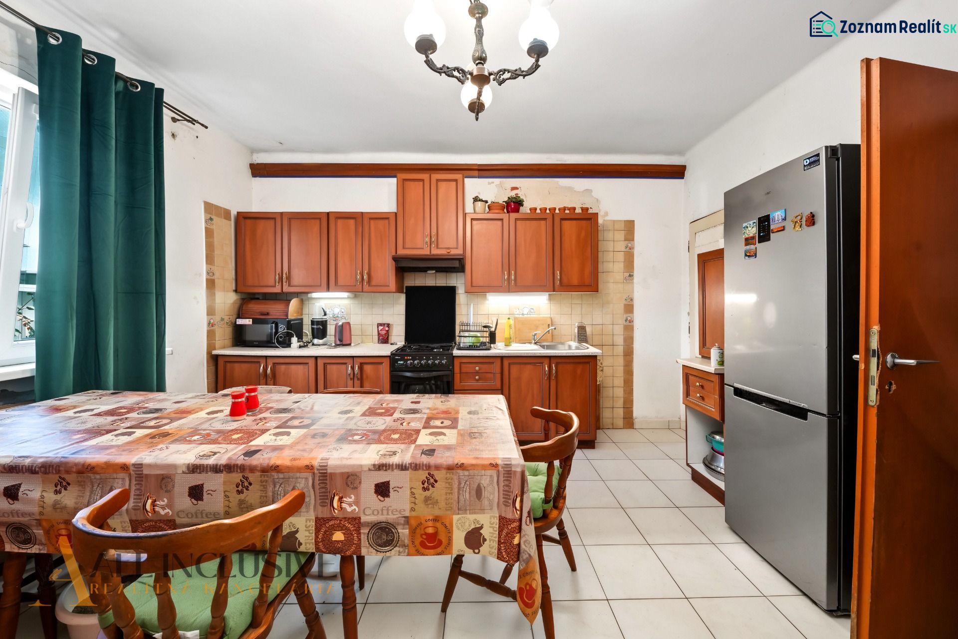 A kitchen in a family house with a dining table, wooden cabinets, and a refrigerator.