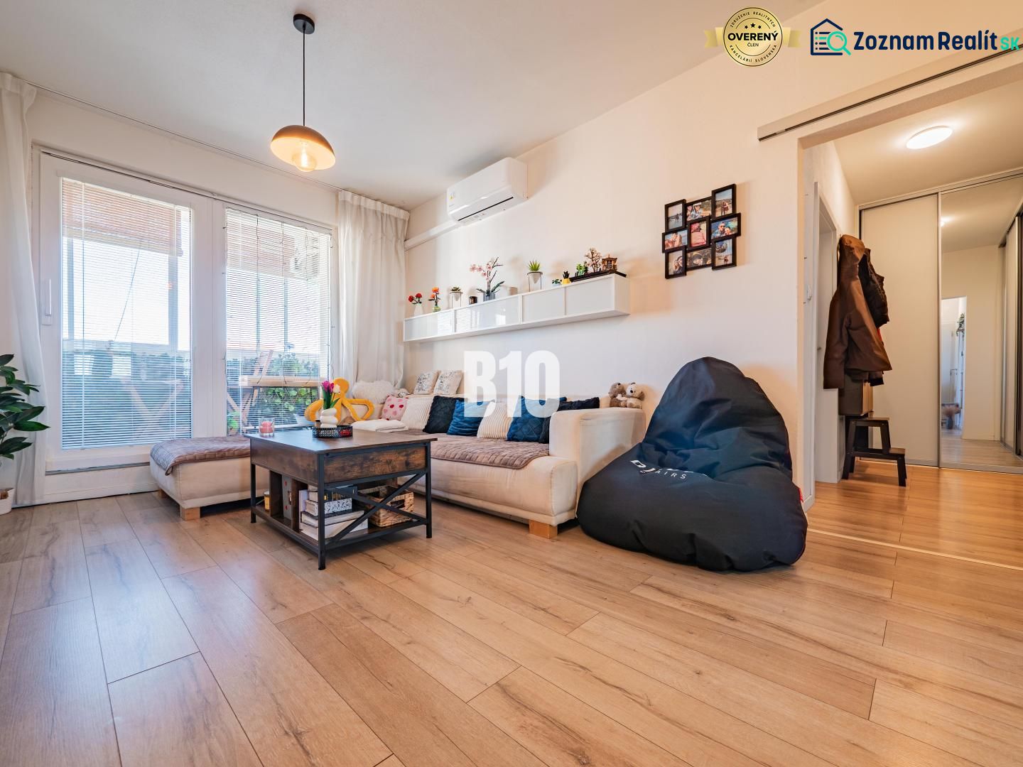 Living room in a 3-room apartment with a wooden decor floor, a sofa, and large windows.