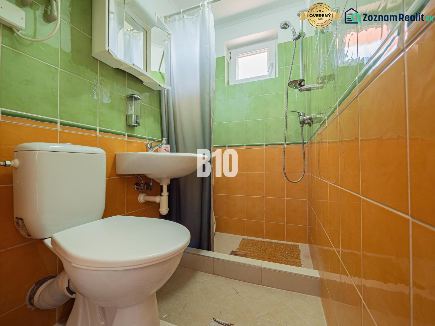 A bathroom in a family house with orange and green tiles and a shower corner.