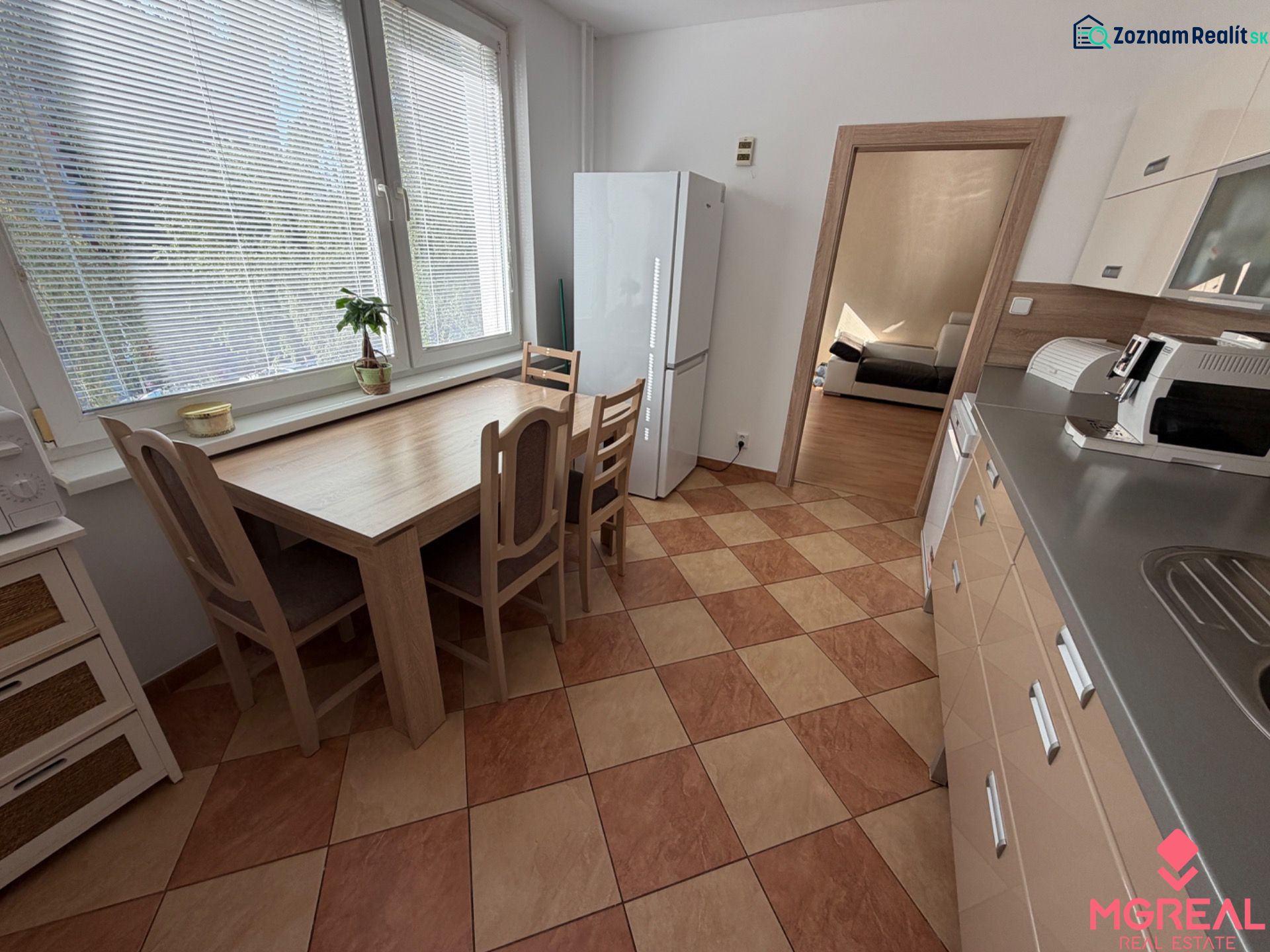 The kitchen in a 3-room apartment with a tiled floor, a dining table, and appliances.