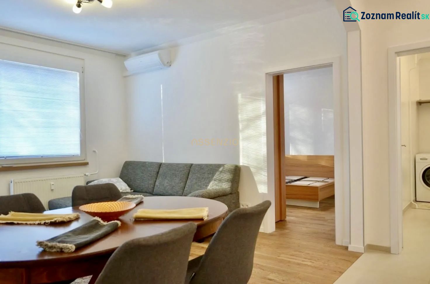 Living room in a 3-room apartment with a sofa, dining table, and wooden decor flooring.