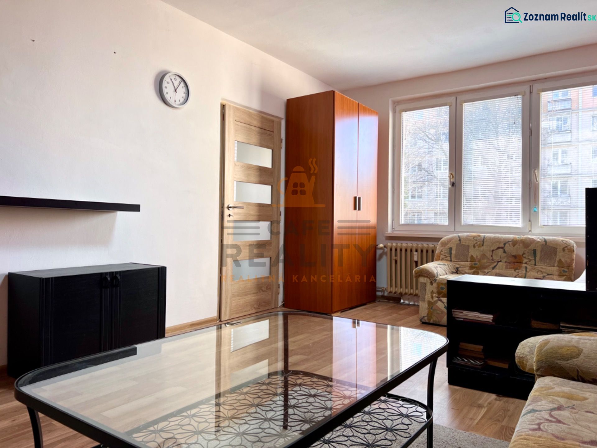 Living room with a sofa, wardrobe, and wooden decor flooring in a 2-room apartment.