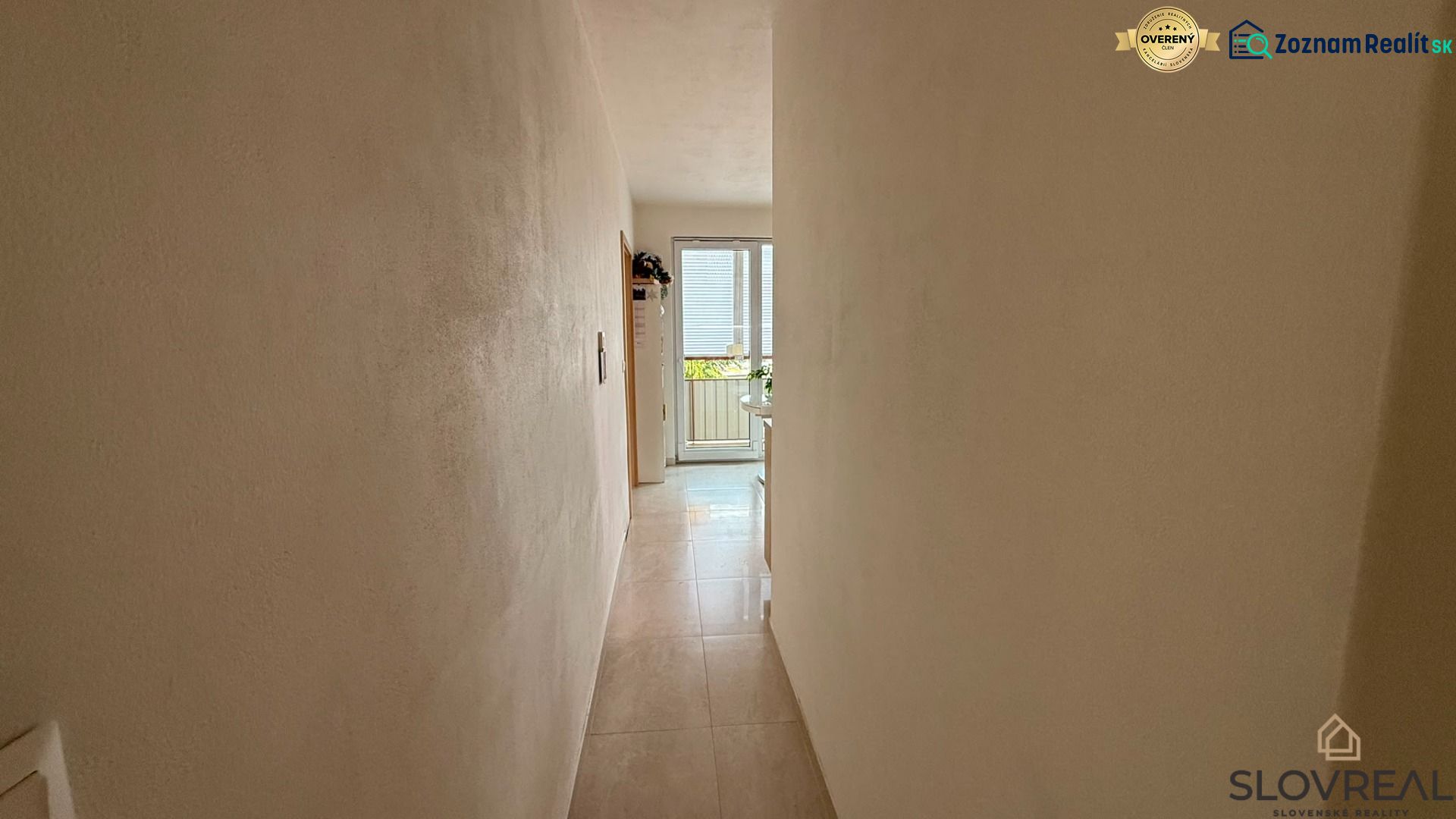 A narrow hallway leading to glass doors in a 4-room apartment.