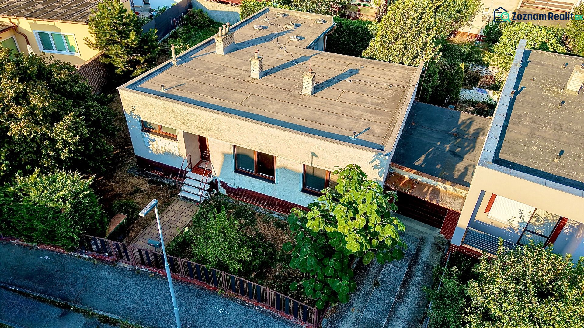 A family house in Nové Zámky with a flat roof, surrounded by greenery and a garden.
