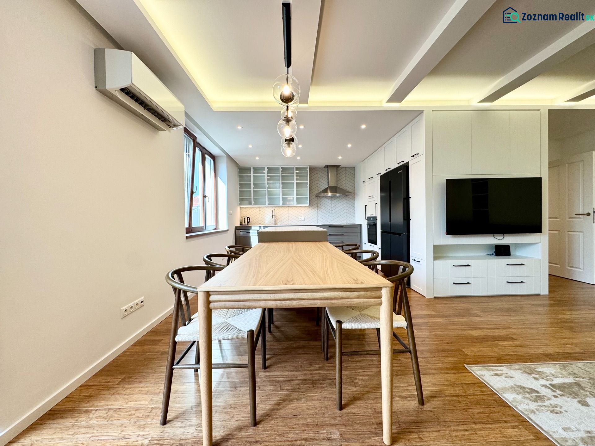 A kitchen in a 3-room apartment with lighting, wood-decor flooring, and a dining table.