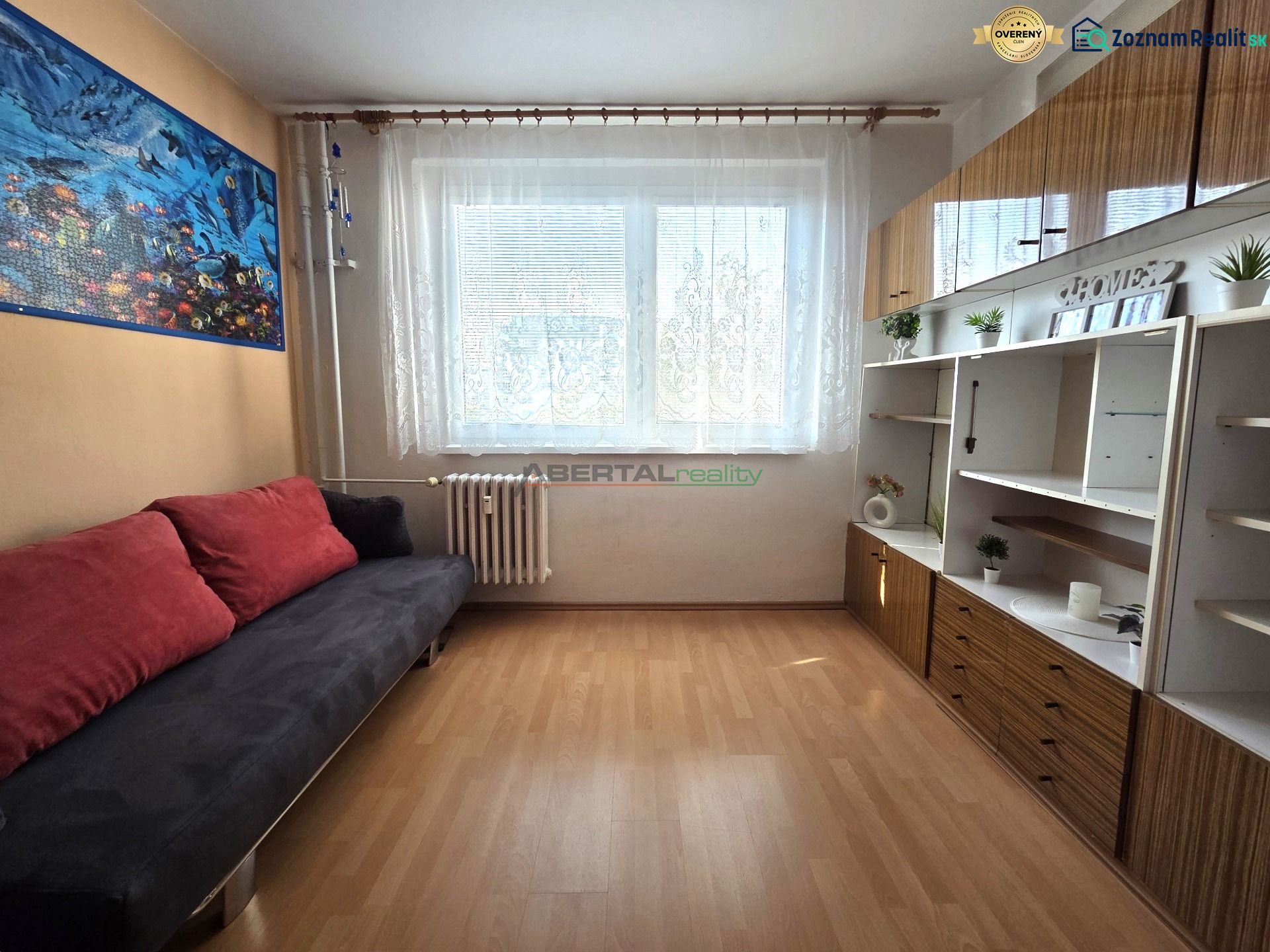 Living room with a sofa, cabinets, and wood-patterned flooring in a 3-room apartment.