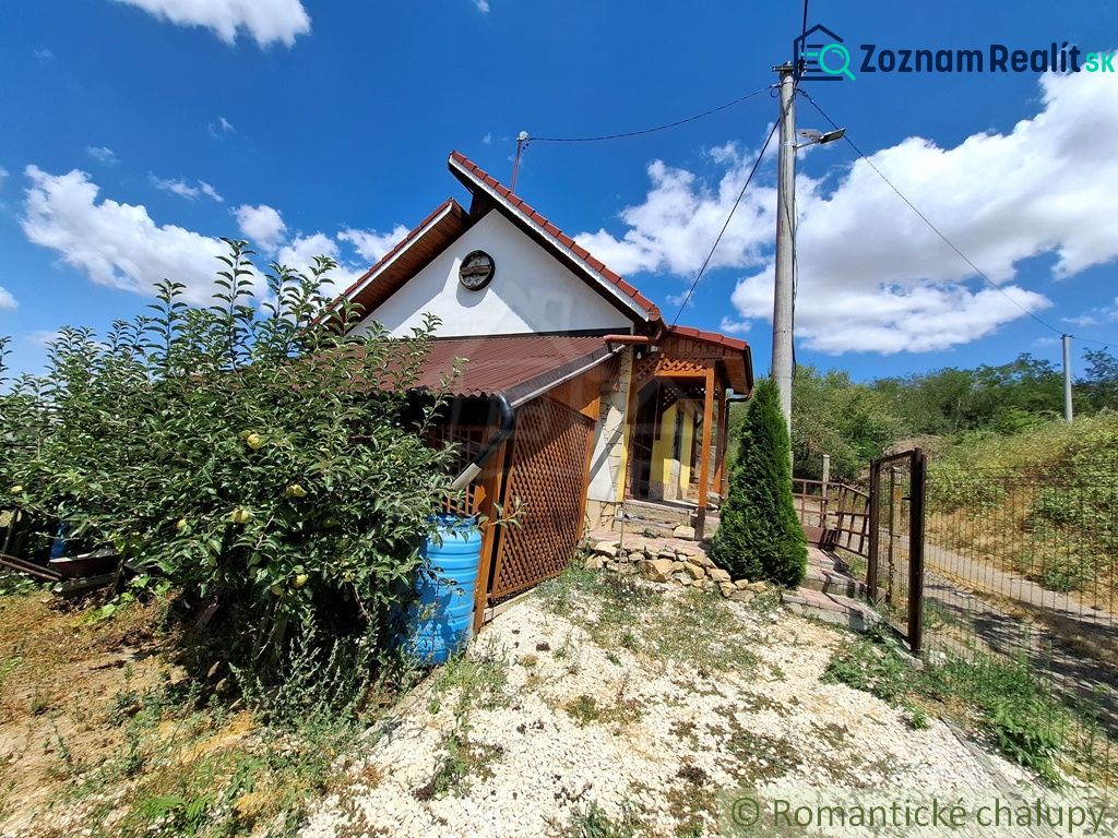 A cottage in Gbelce surrounded by greenery and trees under a blue sky.
