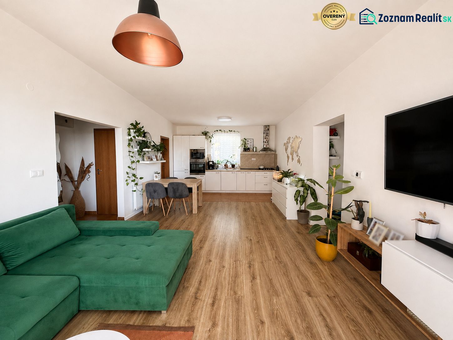 Living room in a 3-room apartment with a wooden decor floor and a green sofa.