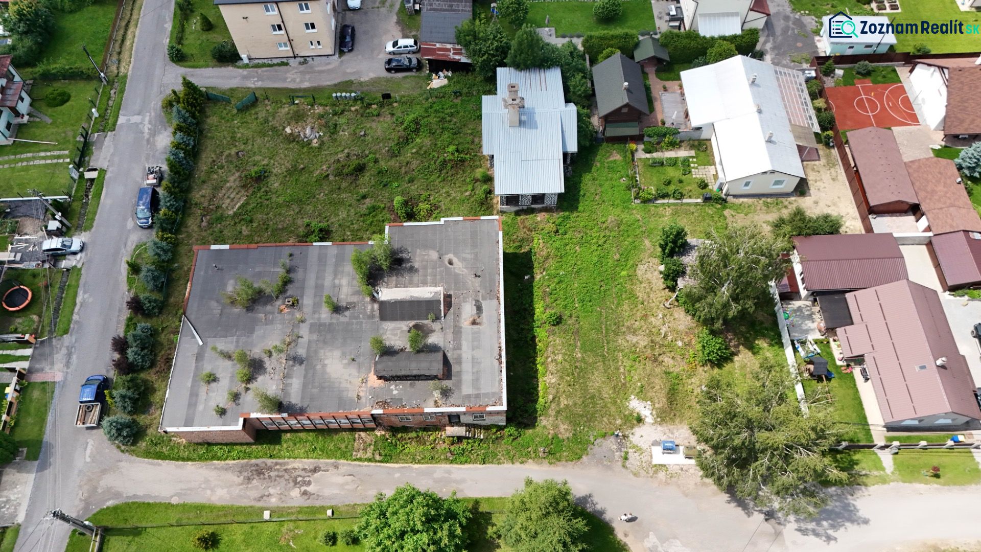 Aerial view of residential plots in Dúbrava with greenery and buildings.