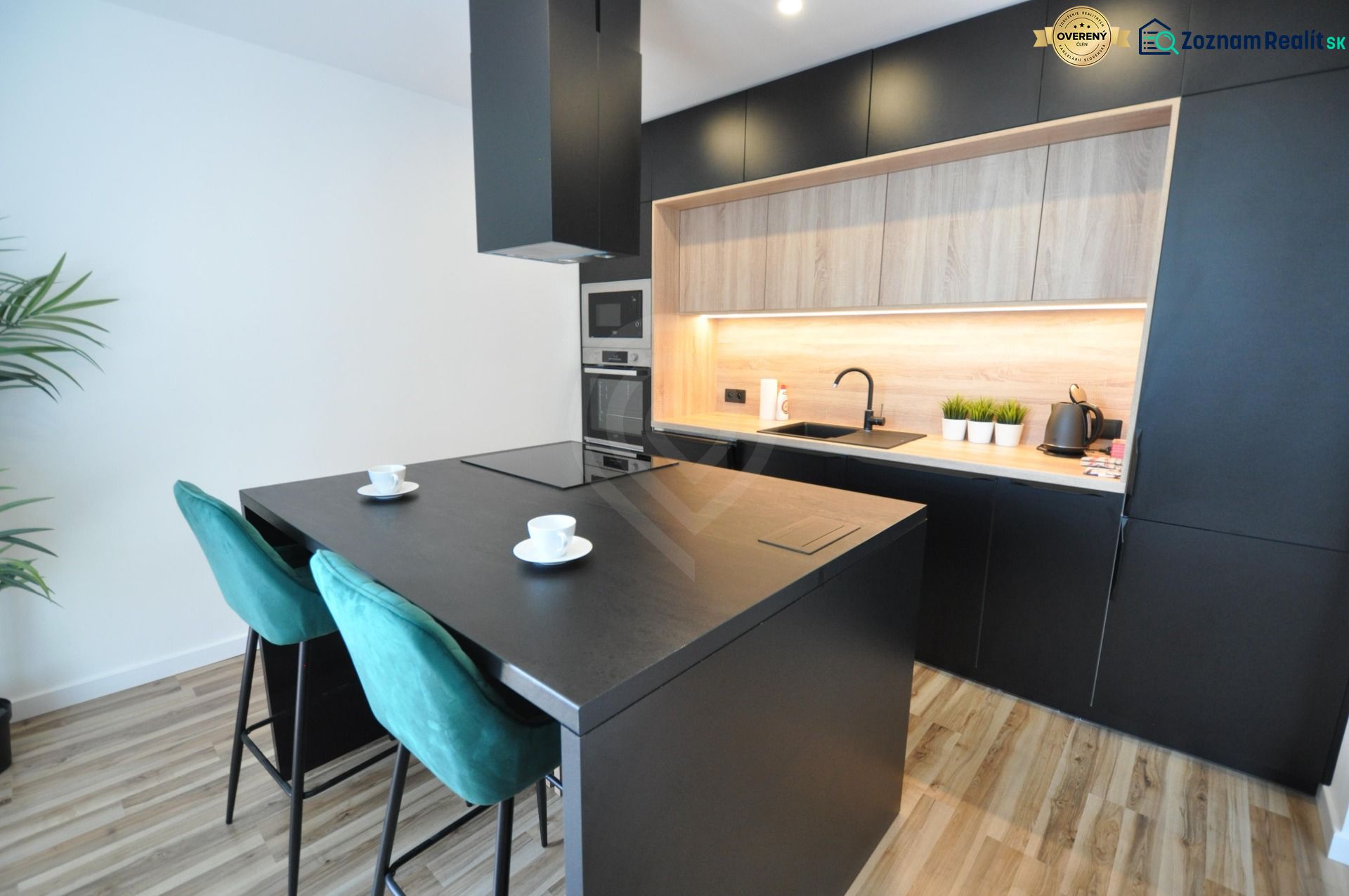 A kitchen in a 3-room apartment with dark cabinets and a wooden decor floor.