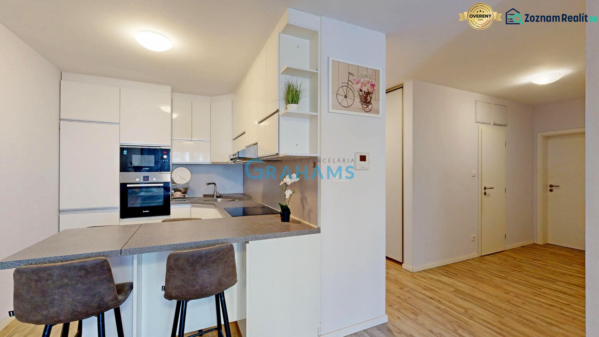 A kitchen with a bar counter and a wooden decor floor in a 3-room apartment.