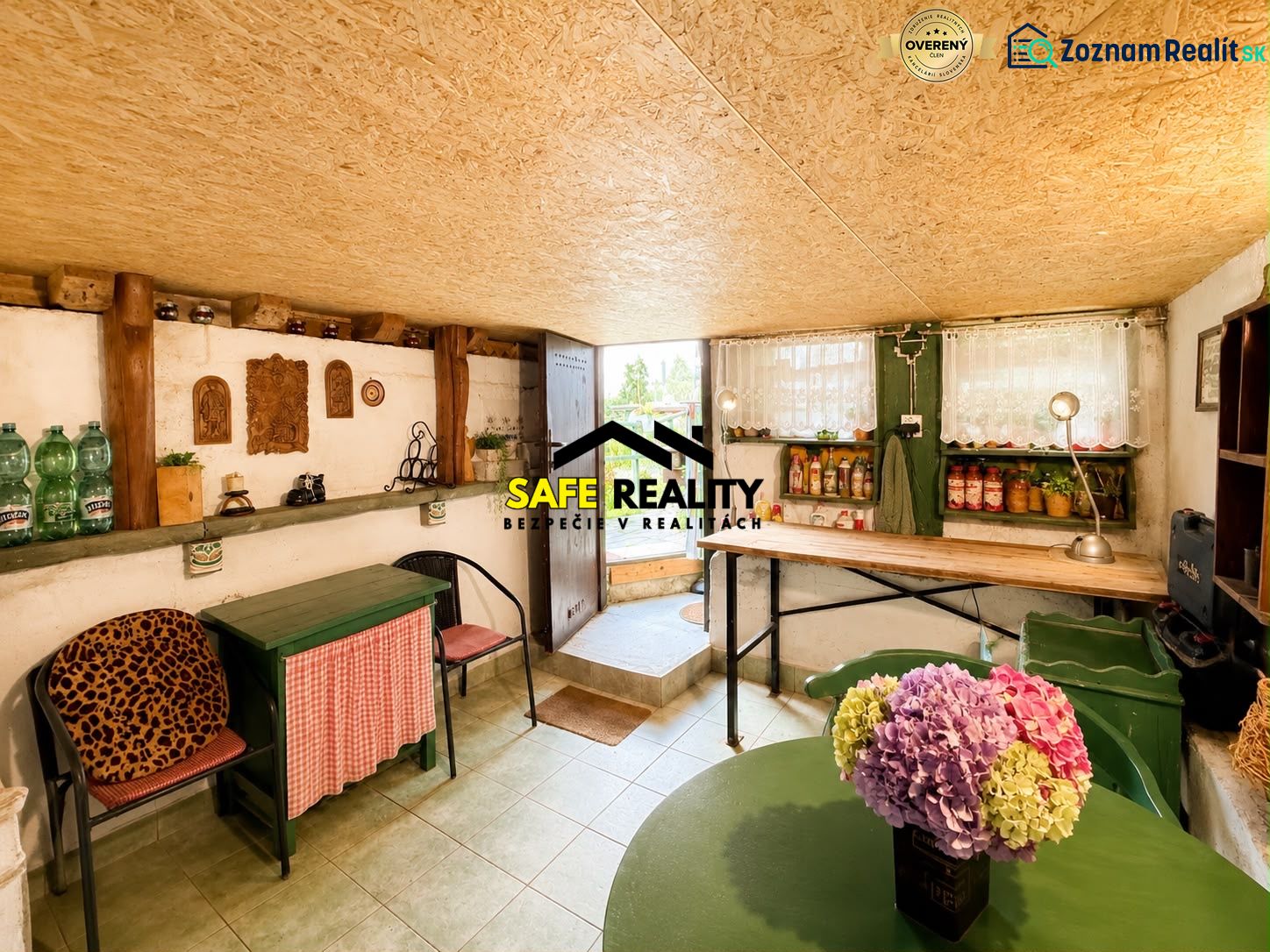 The interior of a cottage with rustic furniture, shelves, and a vase with flowers.