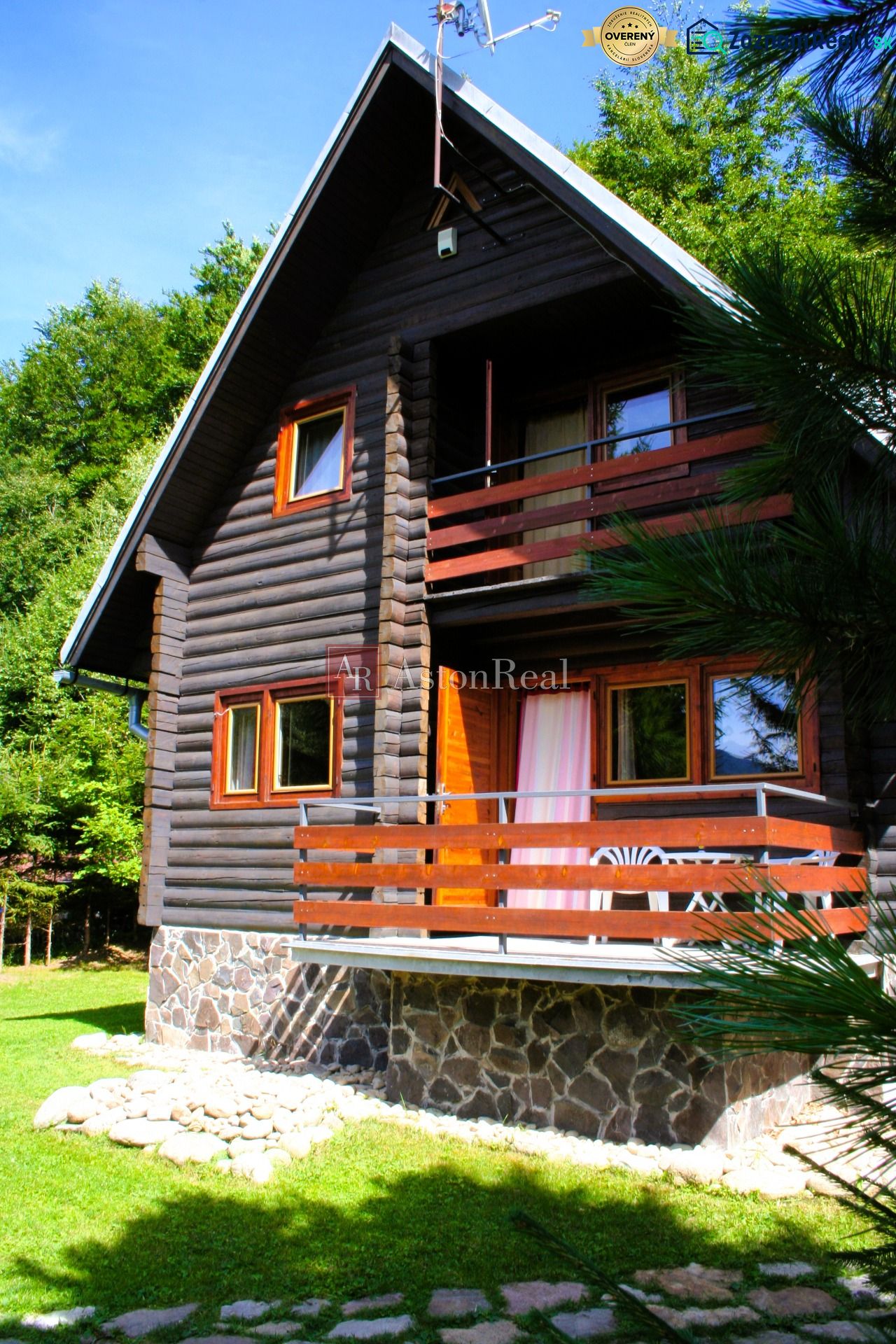 A wooden cabin in Tále near Brezno, surrounded by greenery with a stone plinth and a terrace.