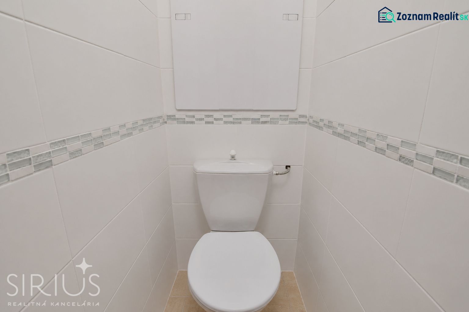 White toilets with patterned tiles and narrow space in commercial premises.
