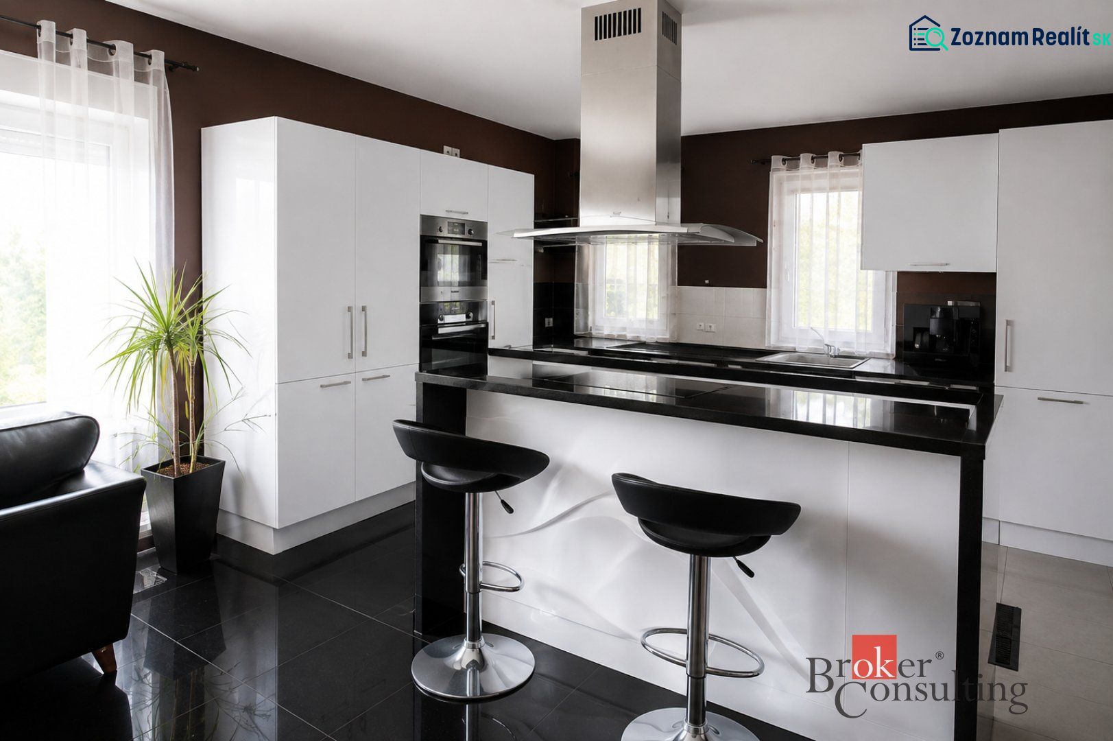 A kitchen in a family house with a bar, black countertops, and white cabinets.
